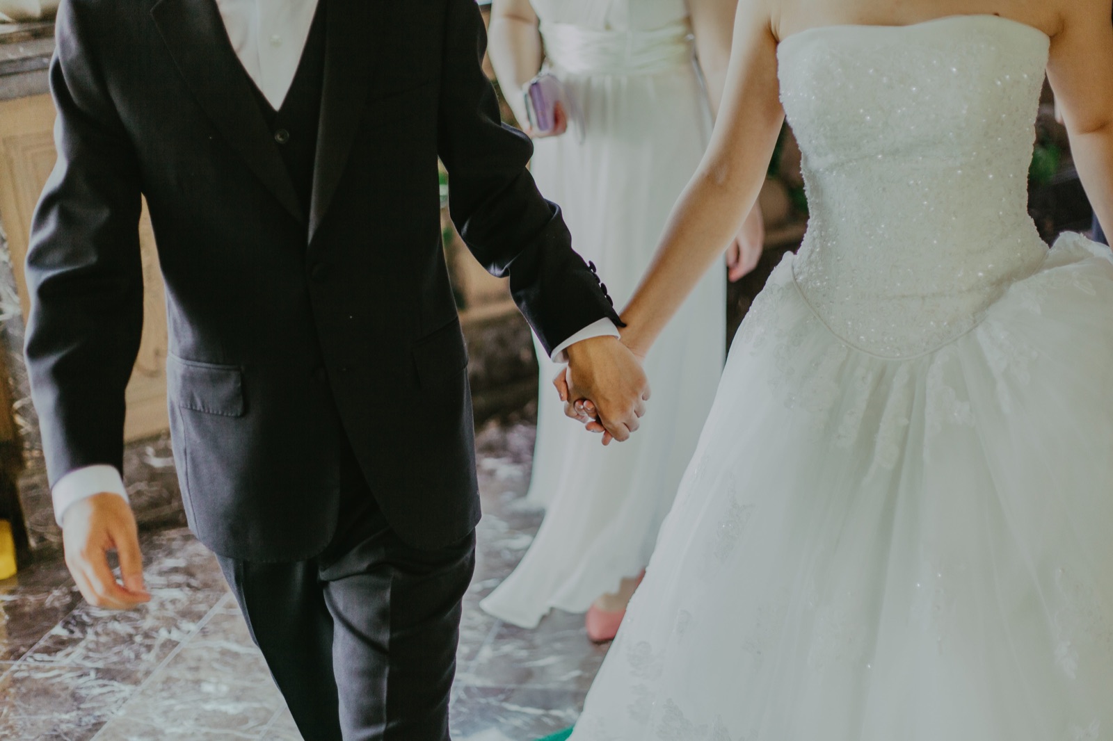 Des mariés se tiennent par la main le jour de leur mariage