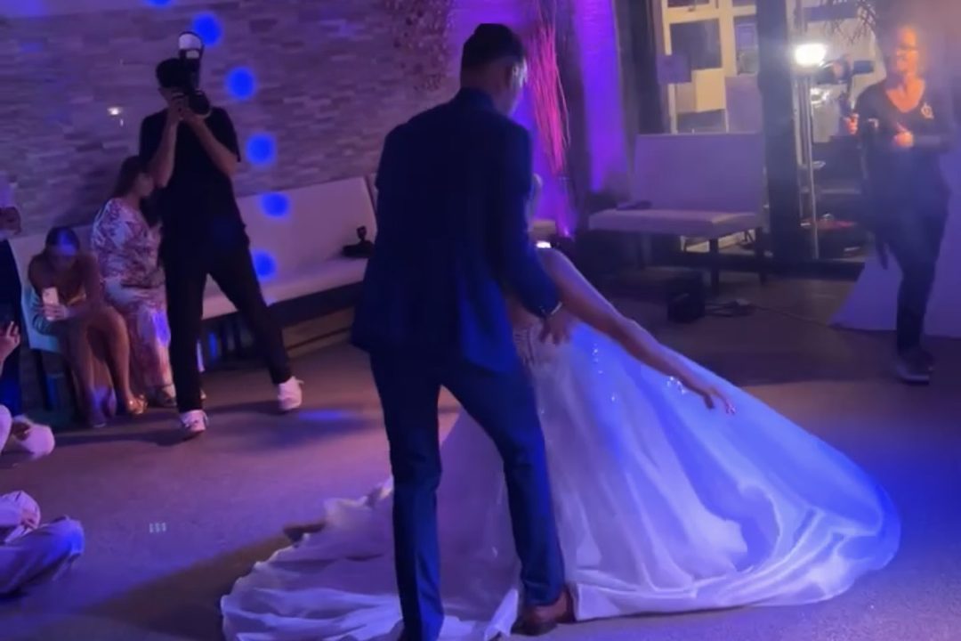 Un couple ouvre le bal de son mariage, la robe déployée sur la piste devant les invités assis